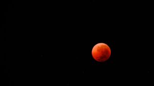 A Blood Moon occurs during a total lunar eclipse when the Earth blocks direct sunlight from reaching the moon.
